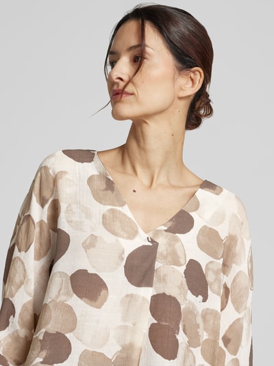 Kobiece model nosi Relaxed Fit Bluse aus Viskose-Mix von Apricot, mieszanka wiskozy, krój relaxed fit, wzór na całej powierzchni, dekolt w serek, rękaw o dł. 3/4, długość tyłu w rozmiarze S: 70 cm, długość rękawów w rozmiarze S: 30 cm, zbliżenie na górną część ciała.