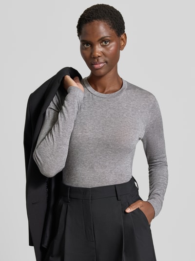 Frauenmodel trägt Longsleeve in melierter Optik von windsor, grauer Lyocell-Woll-Mix, gerader Schnitt, Rundhalsausschnitt, Label-Applikation, Ganzkörperansicht von vorne.