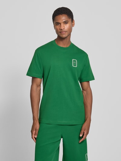 Männermodel trägt grünes Regular Fit T-Shirt aus reiner Baumwolle Modell 'CN Tenniscourt Backprint' von Lacoste, Herren T-Shirt, Ganzkörperansicht von vorne.