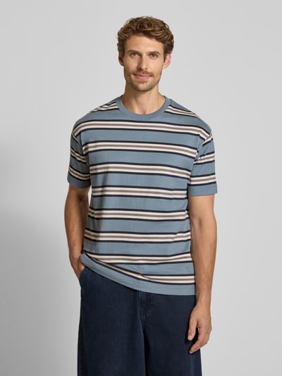 Männermodel trägt Relaxed Fit T-Shirt aus reiner Baumwolle Modell 'ESS ELEVATED' von Marc O'Polo, gestreift in Blau und Beige, Herren T-Shirt, Ganzkörperansicht von vorne.
