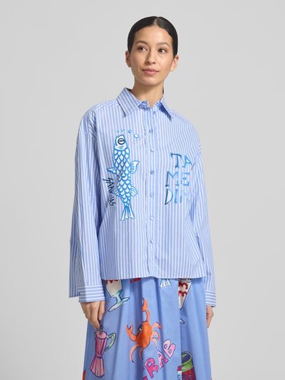 Frauenmodel trägt Regular Fit Hemdbluse mit Viskose-Anteil und Statement-Print von Milano Italy im Baumwoll-Viskose-Mix, Relaxed-Fit, Hemdblusenkragen, Durchgehende Knopfleiste, Langärmelig, überschnittene Schultern, blaue und weiße Streifen mit buntem Print, Ganzkörperansicht von vorne.