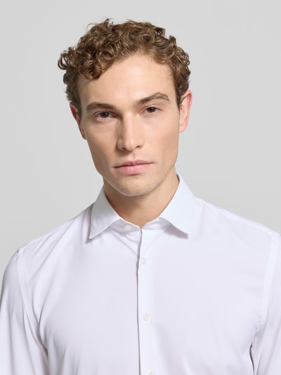 Männermodel trägt Super Slim Fit Business-Hemd mit Knopfleiste von Jake*s, weiß, Kentkragen, Material-Mix mit Stretch-Anteil, Nahaufnahme Oberkörper.