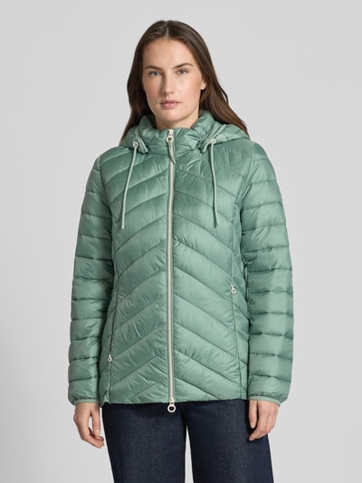 Frauenmodel trägt Regular Fit Steppjacke mit abnehmbarer Kapuze von s.Oliver RED LABEL in Uni-Optik, Reißverschlusstaschen, Ganzkörperansicht von vorne.