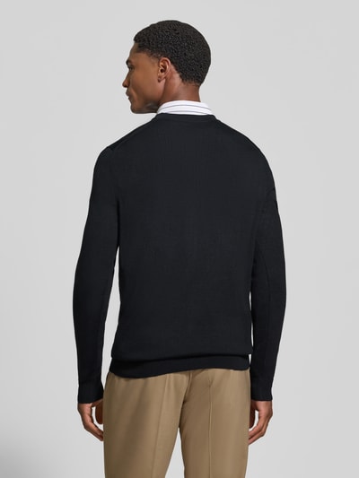 Männermodel trägt Cardigan aus Woll-Mix mit V-Ausschnitt von Christian Berg Men, körpernaher Schnitt, schwarze Farbe, Ganzkörperansicht Rückansicht.