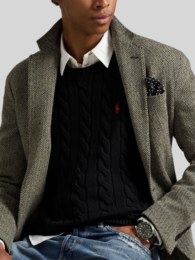 Mężczyzna nosi Regular Fit Strickpullover aus reiner Baumwolle od Polo Ralph Lauren, czarny, dzianinowy, wzór warkoczowy, widoczne logo, okrągły dekolt, długi rękaw, wykończenia prążkowane, widok na górną część ciała z przodu.