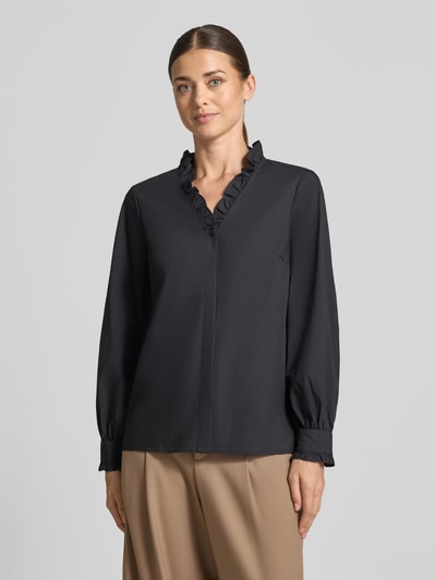 Frauenmodel trägt Regular Fit Langarmbluse aus Baumwoll-Mix von MORE & MORE, schwarzer Stoff, Stehkragen mit Rüschen, Ganzkörperansicht von vorne.