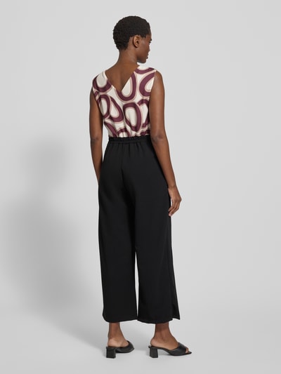 Frauenmodel trägt Jumpsuit mit Eingrifftaschen Modell 'Bi44lina' von ZABAIONE, Material-Mix mit Stretch-Anteil, weites Bein, V-Ausschnitt, schwarze Hose, gemusterter creme-bordeauxfarbener Rücken, Ganzkörperansicht Rückansicht.