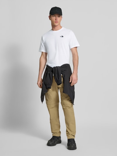 Männermodel trägt Regular Fit T-Shirt aus Baumwoll-Mix Modell 'EVOLUTION' von The North Face, weiß, mit Label-Detail, Ganzkörperansicht von vorne.