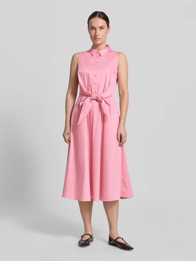 Frauenmodel trägt Hemdblusenkleid aus Satin in Midilänge von Comma, elastischer Baumwoll-Mix, taillierte Passform, ärmelloses Design in Rosa mit durchgehender Knopfleiste und abnehmbarem Taillenband, Ganzkörperansicht von vorne.