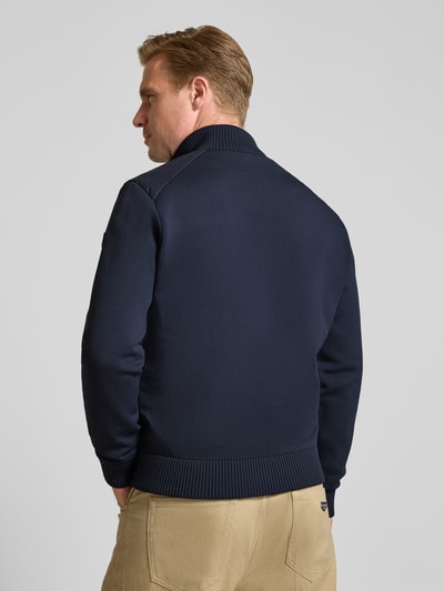 Männermodel trägt dunkelblaue Steppjacke mit geripptem Stehkragen Modell 'SEDUM' von Save The Duck, Strukturmix, Rückansicht, Ganzkörperansicht.