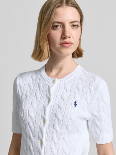 Frauenmodel trägt Regular Fit Strickjacke aus reiner Baumwolle von Polo Ralph Lauren, Optik: Unifarben, Zopfmuster, Logo-Stitching, Crew Neck, Kurzarm, Passform: Regular Fit, Materialverarbeitung: Strick, Nahaufnahme Oberkörper.
