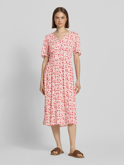 Frauenmodel trägt A-Linien Midikleid aus reiner Viskose Modell 'TALA' von Pieces mit Allover-Muster, kurzen Ärmeln und V-Ausschnitt, Ganzkörperansicht von vorne.