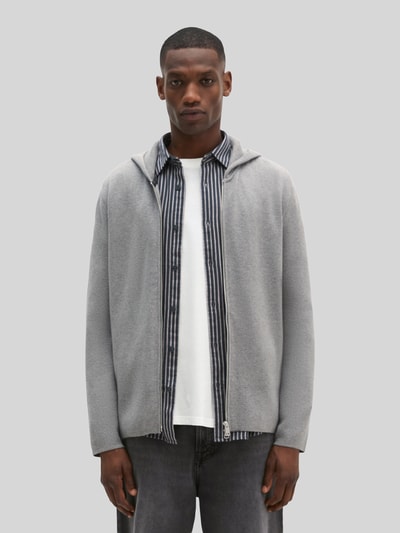 Männermodel trägt Regular Fit Pullover aus reiner Baumwolle von Marc O'Polo in Hellgrau über gestreiftem Hemd, Ganzkörperansicht von vorne.