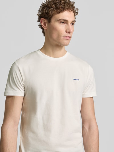 Männermodel trägt T-Shirt mit Label-Detail von Gant, cremefarben, reine Baumwolle, gerader Schnitt, Nahaufnahme Oberkörper.