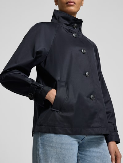 Frauenmodel trägt Jacke mit Stehkragen und Ärmelriegeln von Fuchs Schmitt, dunkelblauer Baumwoll-Mix, Eingrifftaschen, Nahaufnahme Oberkörper.