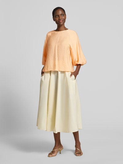 Frauenmodel trägt Regular Fit Bluse aus Viskose-Mix mit 3/4-Arm von Christian Berg Woman in Apricot, strukturierte Oberfläche, Ganzkörperansicht von vorne; Damen Bluse, Rundhalsausschnitt, Rückenlänge 56 cm, Ärmellänge 44 cm, Größe 36, fließende Form.
