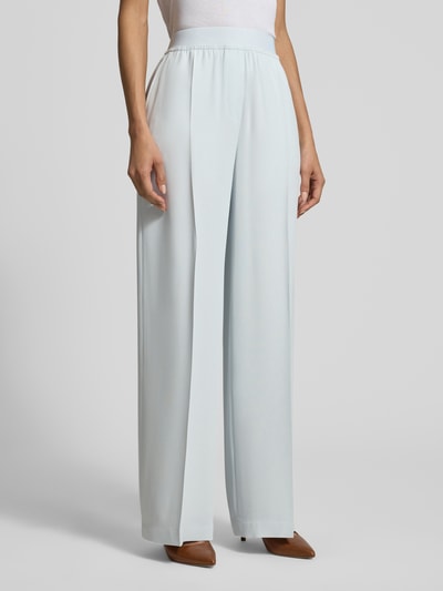 Frauenmodel trägt Weite Hose aus reiner Viskose Modell 'TIANA10' von BOSS in Hellblau, unifarben, Wide Leg, mit Bügelfalten und Label-Applikation, elastischer Bund, seitliche Eingrifftaschen, Ganzkörperansicht von vorne.
