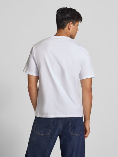 Männermodel trägt Regular Fit T-Shirt aus reiner Baumwolle Modell 'Denver' von JACK & JONES in Weiß und klassische Jeans, Ganzkörperansicht Rückansicht. Herren T-Shirt mit Logo-Print, Rückenlänge bei Größe M 69 cm.