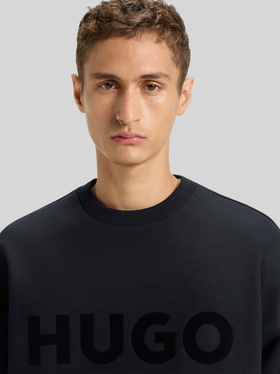 Männermodel trägt Oversized Sweatshirt aus reiner Baumwolle Modell 'DINEX' von HUGO in Unifarben mit Label Print, Nahaufnahme Oberkörper.