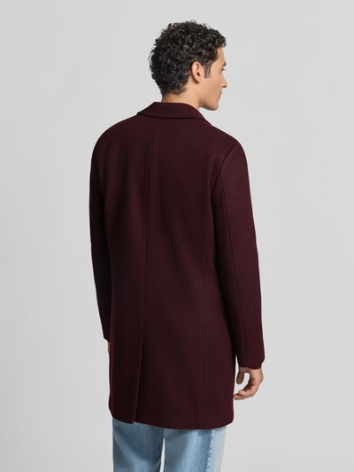 Männermodel trägt Relaxed Fit Mantel aus reiner Baumwolle von MCNEAL in Dunkelrot mit Reverskragen, Knopfleiste, Rückenansicht, Ganzkörperansicht Rückansicht.