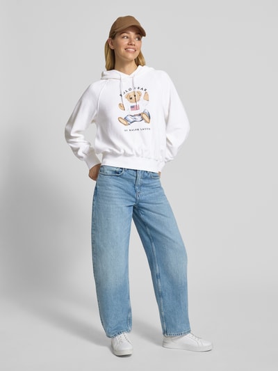 Frauenmodel trägt weißen Regular Fit Hoodie mit Polo-Bear-Print von Polo Ralph Lauren aus Baumwoll-Mix, Frottee, Ganzkörperansicht von vorne.