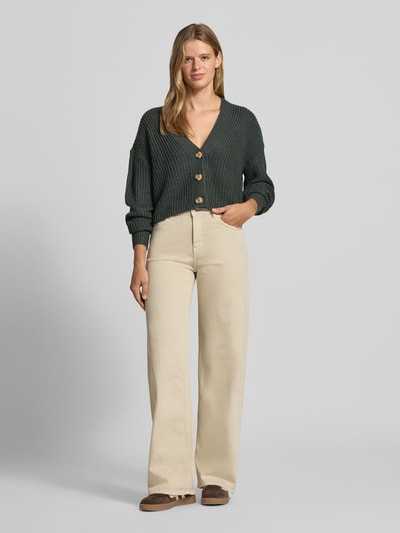 Vrouwenmodel draagt boxy fit gebreid jack met v-hals model 'CAROL' van ONLY in donkergroen, Dames, lichte beige broek, geheellichaamsvooraanzicht.