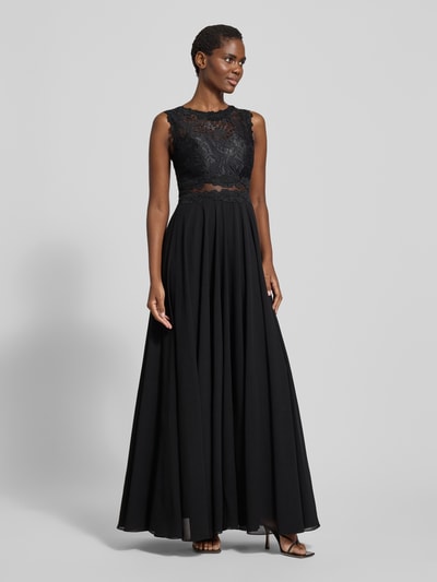 Frauenmodel trägt Abendkleid mit Spitze und Rundhalsausschnitt von Mascara, Maxikleid, schwarze A-Linie, Rückenlänge 153 cm, Brustweite 33 cm, Ganzkörperansicht von vorne.