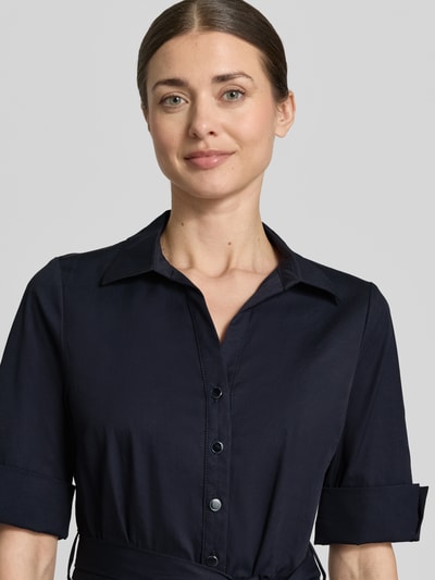 Modelka kobieca nosi Knielanges Hemdblusenkleid mit Bindegürtel von ROBE LÉGÈRE, granatowy kolor, kołnierzyk koszulowy, bawełniany materiał z elastycznym dodatkiem oraz dopasowanym krojem, pasek w talii, krótka lista guzików, rękawy z mankietem, długość do kolan, długość pleców w rozmiarze 36: 104 cm, szerokość w rozmiarze 36: 42 cm, długość rękawa w rozmiarze 36: 30 cm, zbliżenie na górną część ciała