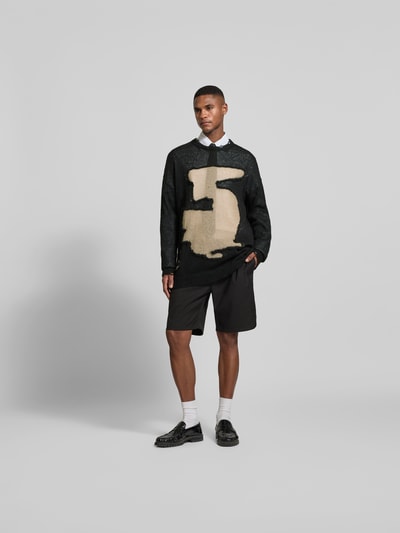 Männermodel trägt Relaxed Fit Longsleeve mit Mohair-Anteil von MM6 Maison Margiela im Used-Look, Strick-Optik, Schwarz-Beige, Ganzkörperansicht von vorne.