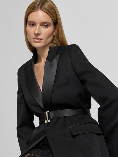 Frauenmodel trägt Blazer mit Schurwoll-Anteil von Victoria Beckham in Schwarz, Material-Mix, Reverskragen, Taillenband, Nahaufnahme Oberkörper.
