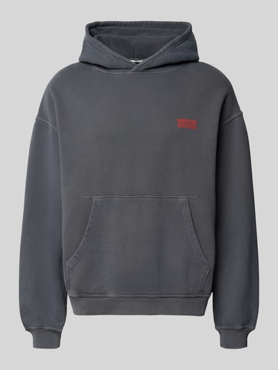Produktfoto, Hoodie mit Logo Modell 'PLIZZY' von American Vintage z bawełny, krój relaxed fit, kieszeń kangurka, długość tyłu 66 cm, długość rękawów 60 cm, kolor ciemnoszary, logo czerwone