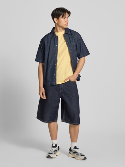 Männermodel trägt Regular Fit T-Shirt aus reiner Baumwolle Modell 'FRED' von Only & Sons in Gelb, Jersey, Motiv-Print, Ganzkörperansicht von vorne.