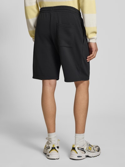 Männermodel trägt Regular Fit Shorts mit Label-Stitching von REVIEW aus Baumwoll-Mix, elastischer Bund, schwarze Farbe, Ganzkörperansicht Rückansicht.