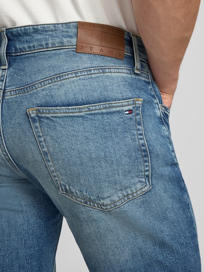 Mężczyznamodel nosi Slim Fit Jeans aus Baumwoll-Mix Modell 'SCANTON SLIM' od Tommy Jeans, denim, logo-stitching, 5-kieszeni, detal tylnej kieszeni, krój slim fit, bawełniany materiał, zdjęcie zbliżeniowe tylnej kieszeni.