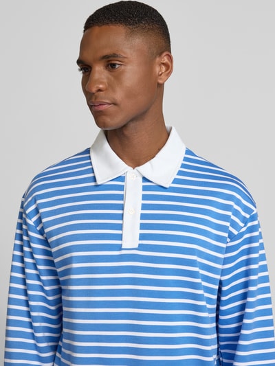 Męski model nosi Relaxed Fit Koszulka polo z listwą guzikową Model 'PERSSON' od Casual Friday, mieszanka bawełny i wiskozy, niebieskie i białe paski, długi rękaw, długość tyłu 66 cm dla rozmiaru M, zbliżenie na górę ciała.