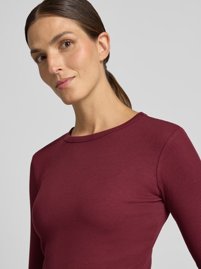Frauenmodel trägt bordeauxfarbenes Slim Fit Langarmshirt aus Baumwoll-Mix Modell 'CHLOE' von VERO MODA, Nahaufnahme Oberkörper.