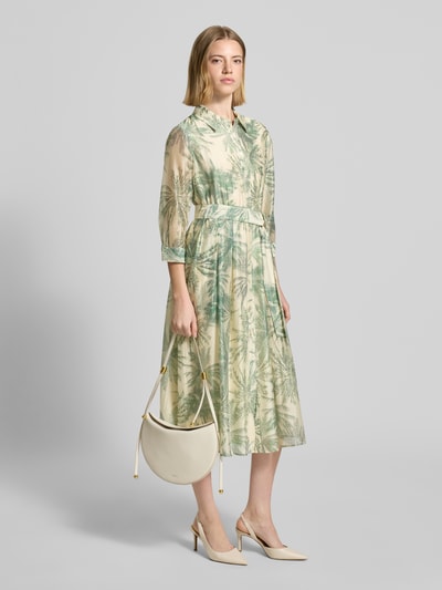 Frauenmodel trägt Figurumschmeichelndes Freizeitkleid aus Lyocell-Mix von s.Oliver BLACK LABEL mit Floralem-Allover-Muster, Midi-Länge, V-Ausschnitt, Knopfleiste, Taillengürtel, 3/4-Arm, Materialverarbeitung Popeline, Viskose-Mix, dezente grün-beige Farbtöne, fließende Textur, Ganzkörperansicht von vorne.