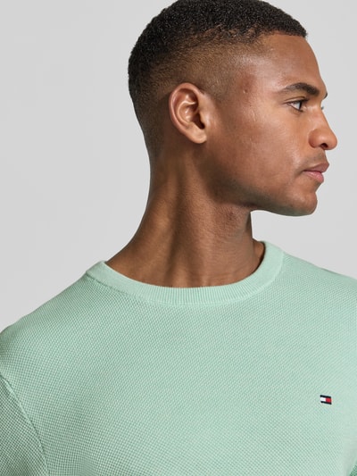 Männermodel trägt Regular Fit Strickpullover aus reiner Baumwolle von Tommy Hilfiger, Optik: Unifarben, Strickoptik, Nahaufnahme Oberkörper.