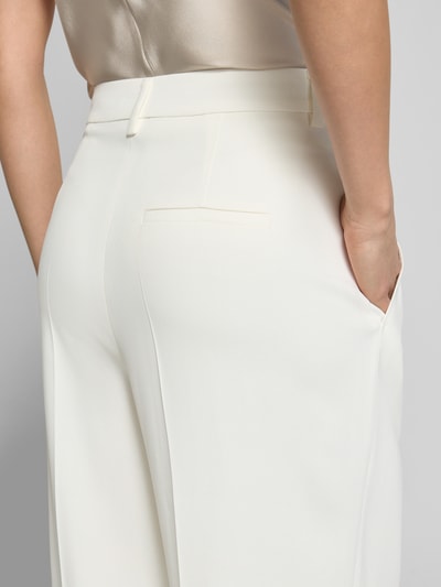 Frauenmodel trägt Wide Fit Stoffhose aus Viskose-Mix mit Bundfalten von Luisa Cerano, cremefarben, glatte Textur, Nahaufnahme Rückansicht.