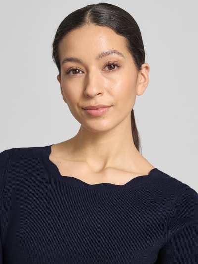 Frauenmodel trägt Strickshirt aus Viskose-Mix mit Rüschenkragen von Christian Berg Woman, strukturierter Stoff in Dunkelblau, Nahaufnahme Oberkörper.