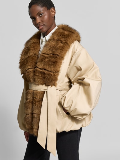 Frauenmodel trägt Jacke mit Kunstfellbesatz von ROTATE, beige mit braunem Kunstfell, Material-Mix, taillierte Passform, Nahaufnahme Oberkörper.