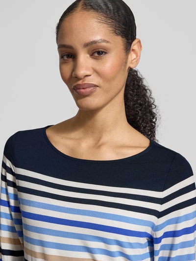 Kobiece modelka nosi Longsleeve aus Viskose-Elasthan-Mix mit 3/4-Arm od Betty Barclay, krój regular fit, okrągły dekolt, długość tyłu 60 cm w rozmiarze 36, paski w odcieniach niebieskiego, beżu i czerni, zbliżenie na górną część ciała.