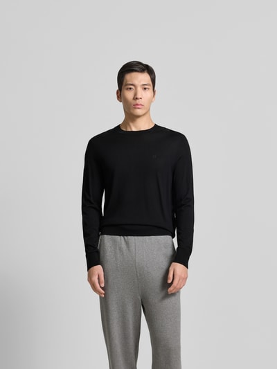 Männermodel trägt Wollpullover aus reiner Wolle von Dsquared2 in Schwarz mit Rundhalsausschnitt und gerippten Abschlüssen, körpernahe Passform, Strick-Optik, Ganzkörperansicht von vorne.