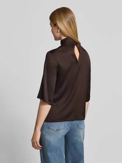 Frauenmodel trägt Regular Fit Bluse mit Stehkragen Modell 'Aletia' von DRYKORN, dunkler elastischer Acetat-Mix, glatte Textur, Ganzkörperansicht Rückansicht.