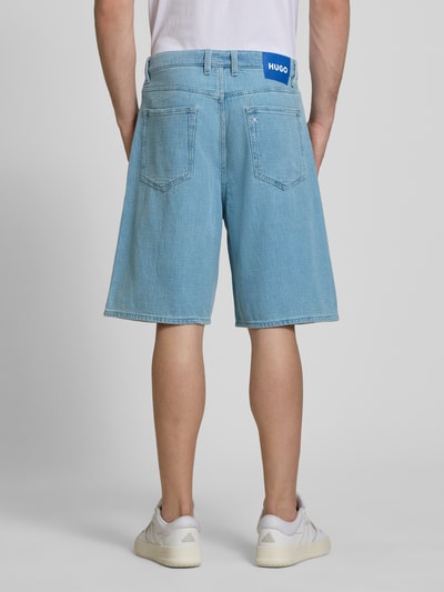 Männermodel trägt Loose Fit Jeansshorts aus reiner Baumwolle Modell 'MASON' von Hugo Blue in Denim-Optik mit Label Patch, Ganzkörperansicht Rückansicht.