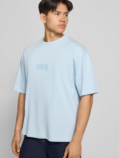 Männermodel trägt T-Shirt mit Label-Stitching und Rundhalsausschnitt von REVIEW, Relaxed-Fit aus Reine Baumwolle, hellblau, Ganzkörperansicht von vorne. Rückenlänge bei Größe M: 70 cm.