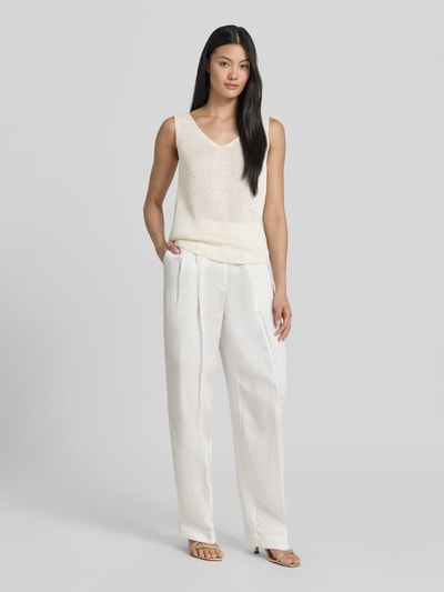 Frauenmodel trägt Regular Fit Top in Strick-Optik von s.Oliver BLACK LABEL in Creme zu weißer Hose, Ganzkörperansicht von vorne.