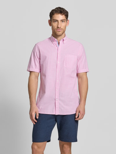 Männermodel trägt Regular Fit Freizeithemd mit Brusttasche von Christian Berg Men in Rosa mit feinen weißen Streifen, Reine Baumwolle, Button-Down-Kragen, kurzärmelig, durchgehende Knopfleiste, Ganzkörperansicht von vorne.