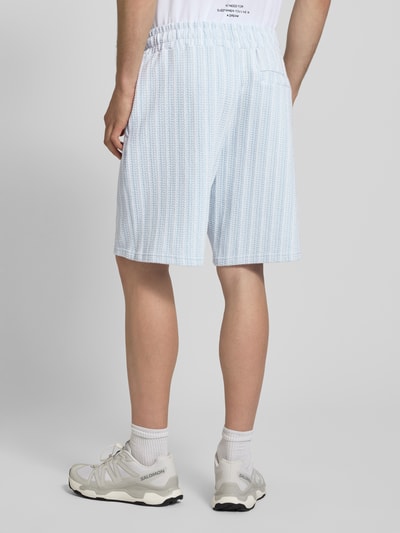 Mężczyzna nosi szorty Straight Fit Shorts mit Strukturmuster Modell 'Forno' od Pegador, bawełna, fakturowany wzór, elastyczny pas, szerokość w rozmiarze M 42 cm, długość wewnętrzna nogawki 23 cm, widok całej sylwetki z tyłu.