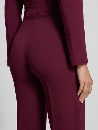 Frauenmodel trägt Flared Fit Stoffhose mit Bügelfalten von Rinascimento in Bordeaux, elastischer Bund, Material-Mix, Detailaufnahme, Nahaufnahme Unterkörper.